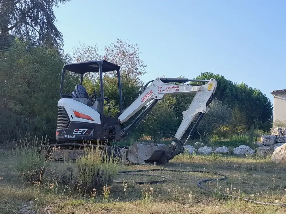 Mini-pelle de location en attente pour chantier de terrassement chez un particulier