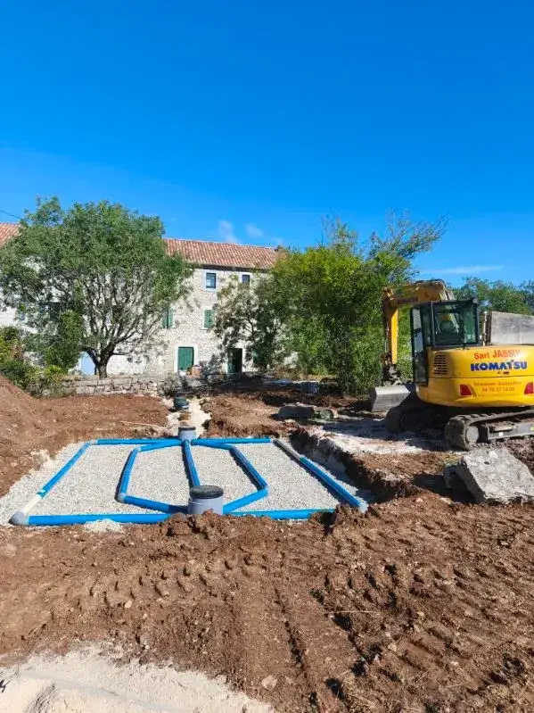 Mise en place d’un réseau d’épandage pour fosse septique devant une maison en pierre