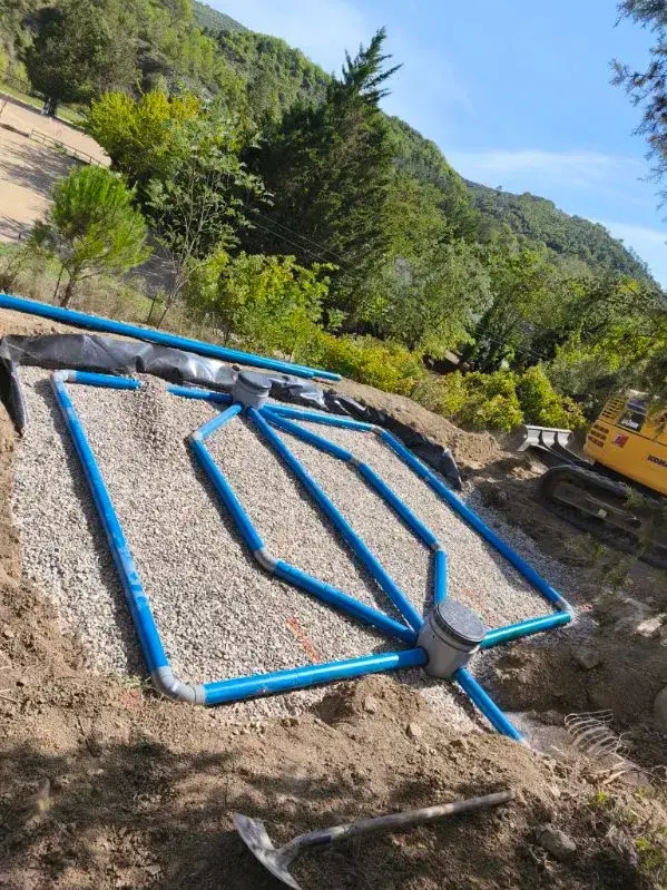 Réseau d’épandage en gravier avec canalisations bleues pour assainissement autonome