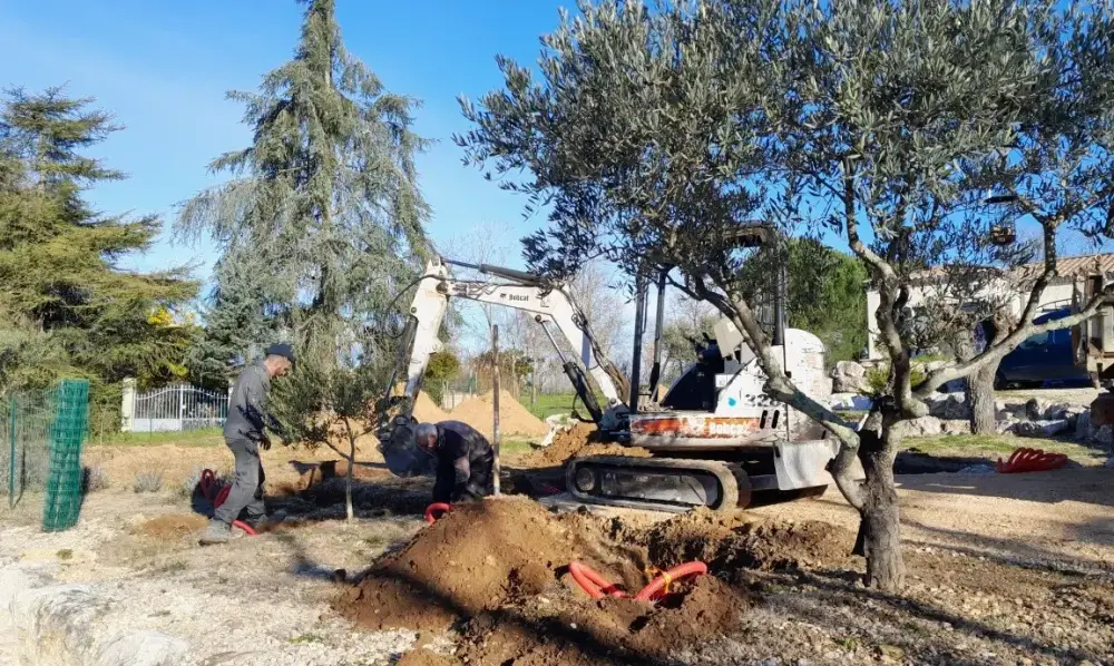 Terrassement paysager avec mini-pelle et camion benne dans un terrain résidentiel